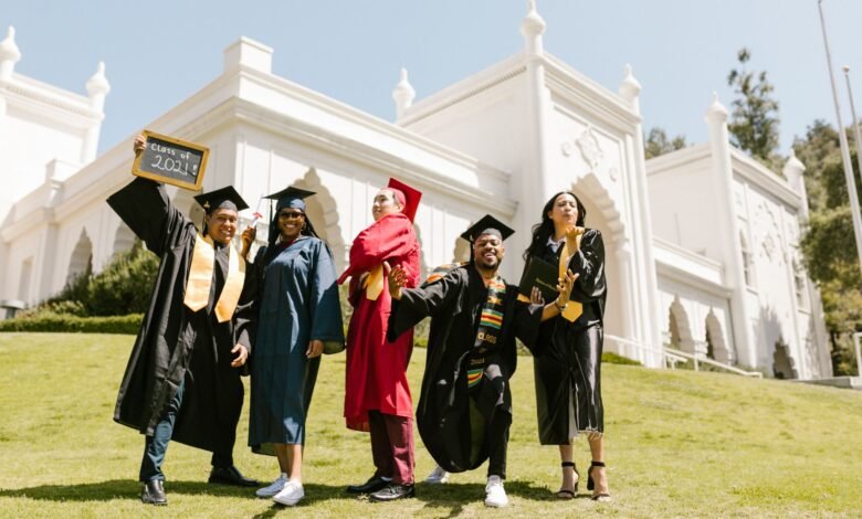 newly graduate students posing at the camera while standing on grass field
