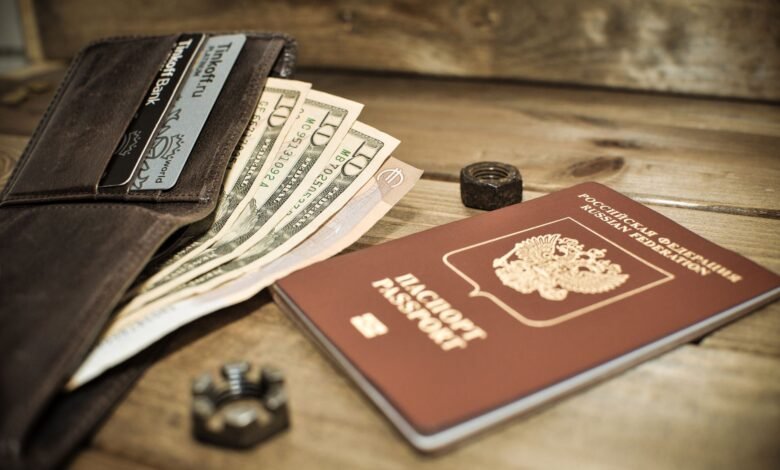 photo of a brown passport beside a wallet with dollar bills