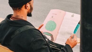 man reading magazine on park bench outdoors