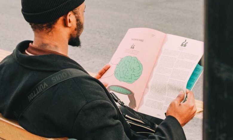 man reading magazine on park bench outdoors