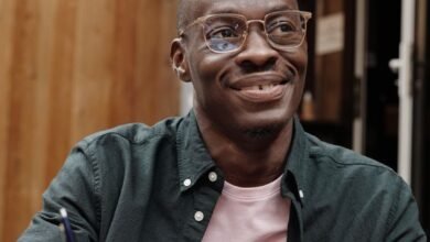 a man wearing eyeglasses holding a pen on a notebook