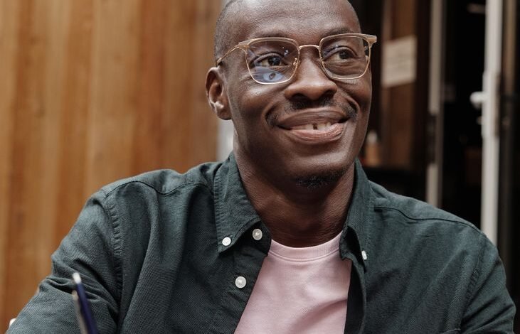 a man wearing eyeglasses holding a pen on a notebook