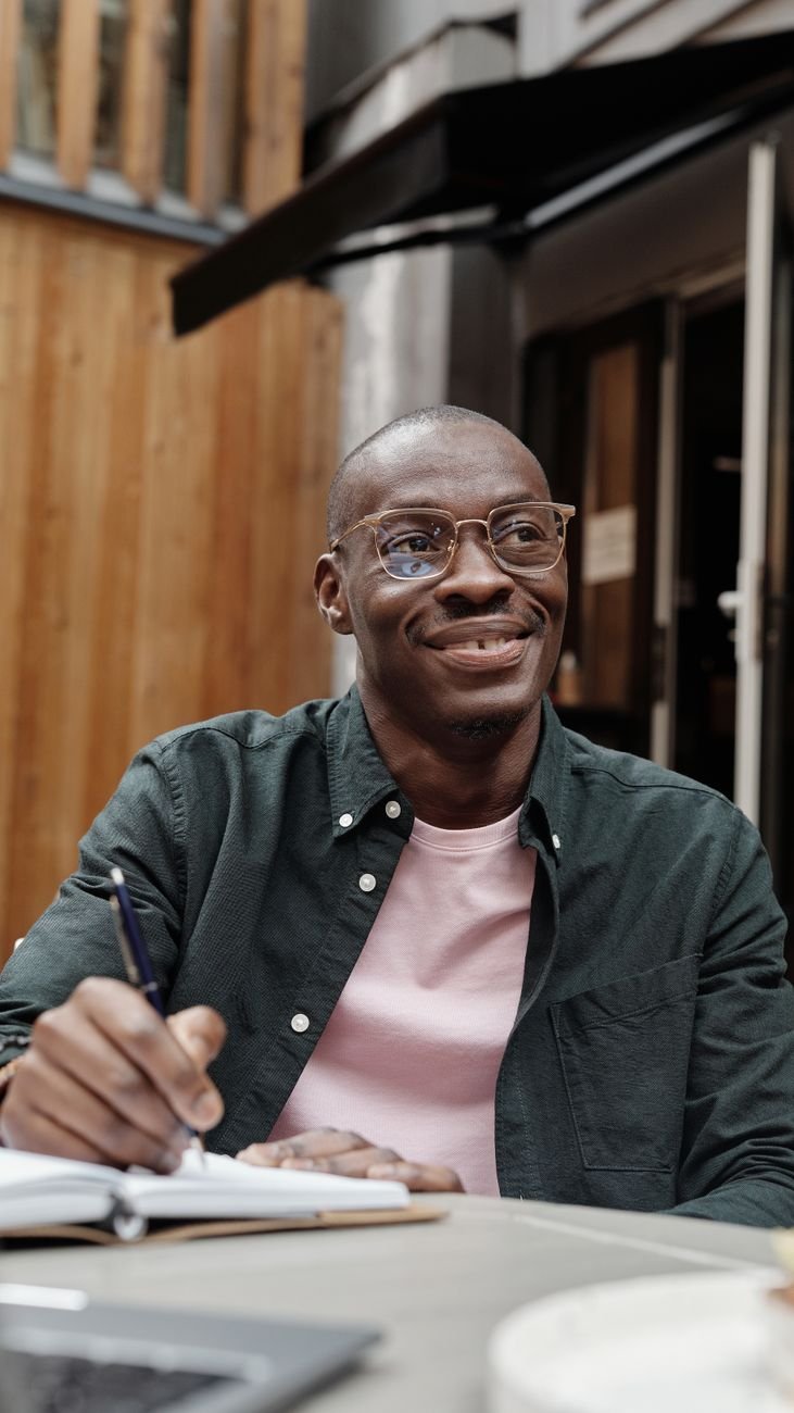 a man wearing eyeglasses holding a pen on a notebook