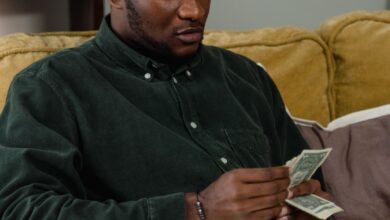 a man in black long sleeves counting his money while sitting on the couch