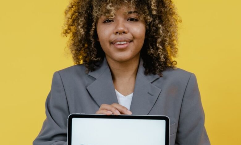 woman holding table computer standing near the yellow background