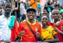 four happy soccer fans in colorful jerseys celebrating