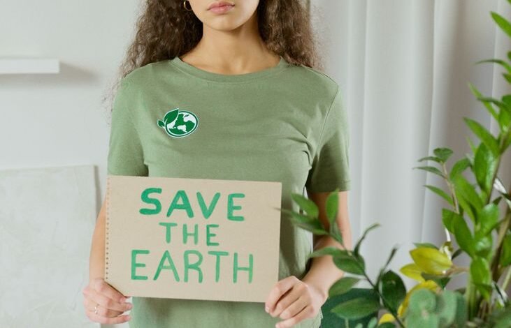 a woman in green shirt holding a save the earth sign