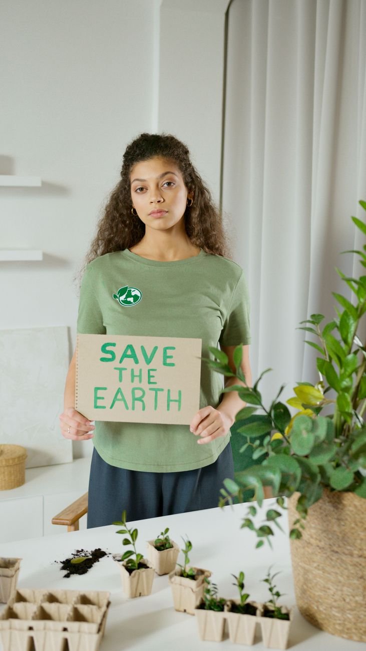a woman in green shirt holding a save the earth sign