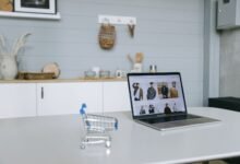 a laptop beside a miniature shopping cart