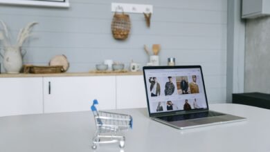 a laptop beside a miniature shopping cart