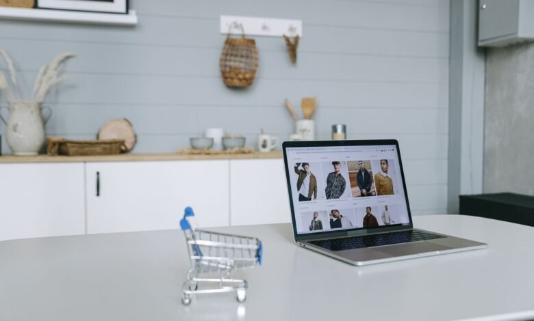 a laptop beside a miniature shopping cart
