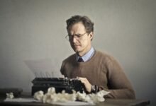 adult frowned male writer working on typewriter at home