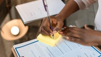 crop photo of woman writing on yellow sticky note pad