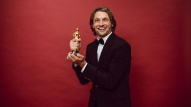 a happy man in a black suit holding his trophy