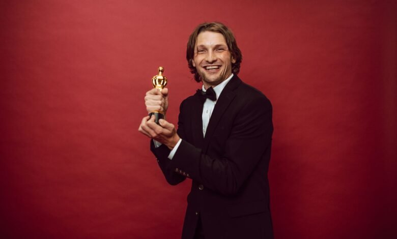 a happy man in a black suit holding his trophy