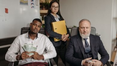 men in business attire sitting near a woman wearing coat and holding documents