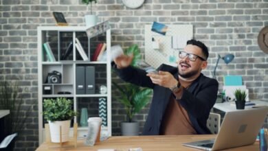 a man sitting at a desk in an office and throwing money
