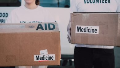 persons wearing volunteer shirts holding cardboard boxes with medicine labels