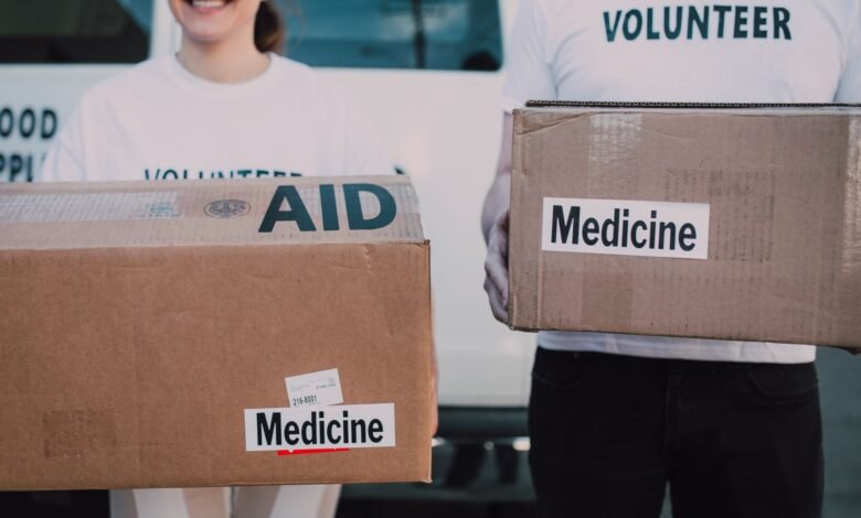 persons wearing volunteer shirts holding cardboard boxes with medicine labels