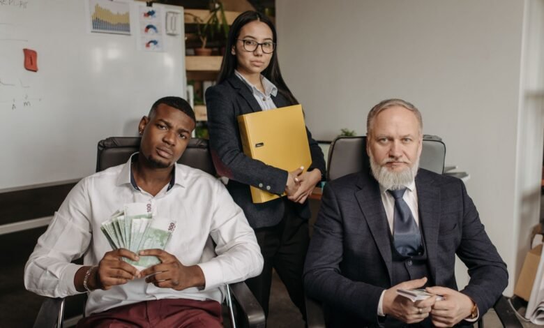 men in business attire sitting near a woman wearing coat and holding documents