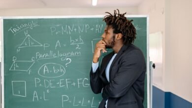 a teacher in black coat contemplating by the blackboard