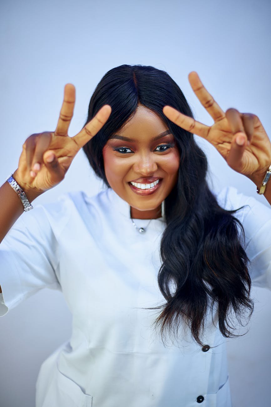 smiling woman making peace sign in white coat