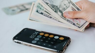 crop faceless person with cash and calculator app on smartphone