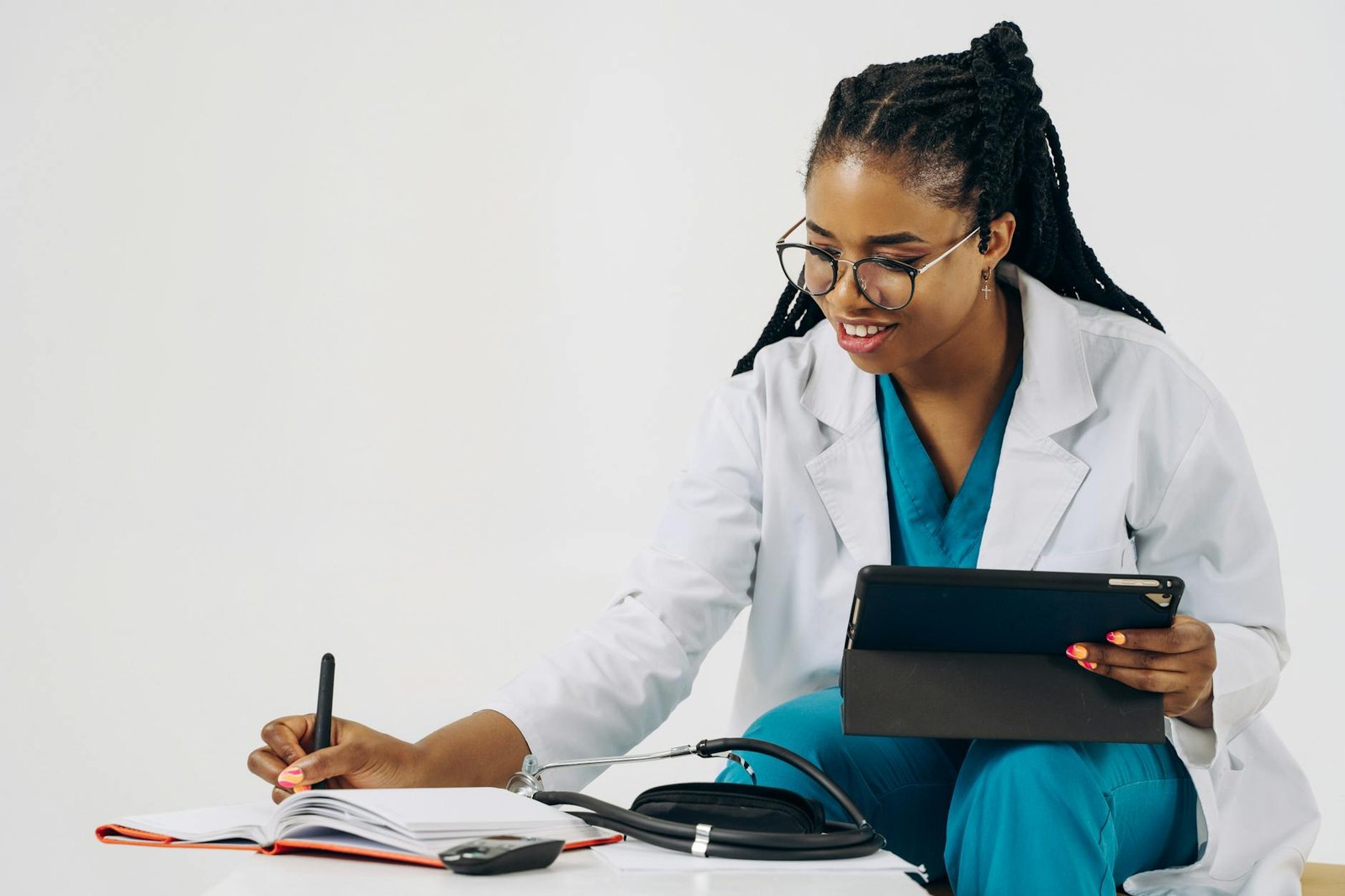 doctor using a tablet and taking notes in a notebook