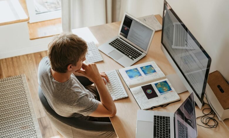 high angle shot of a boy sitting on grey chair while using his laptop computers