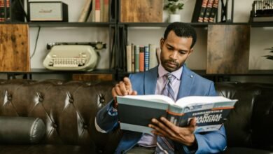 a man in corporate attire reading a book on a couch