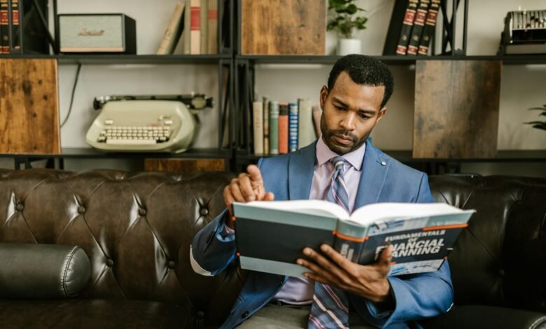 a man in corporate attire reading a book on a couch