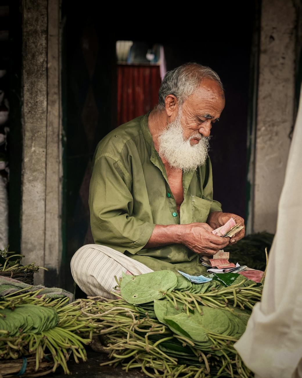 elderly vendor selling betel leaves at market