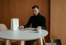 man in black sweater sitting at table using digital tablet