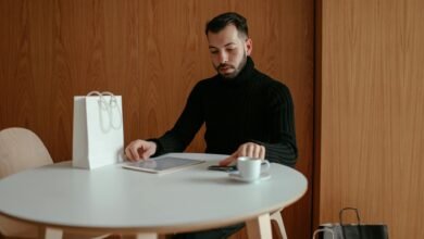 man in black sweater sitting at table using digital tablet