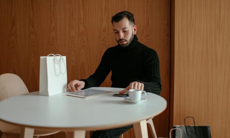 man in black sweater sitting at table using digital tablet