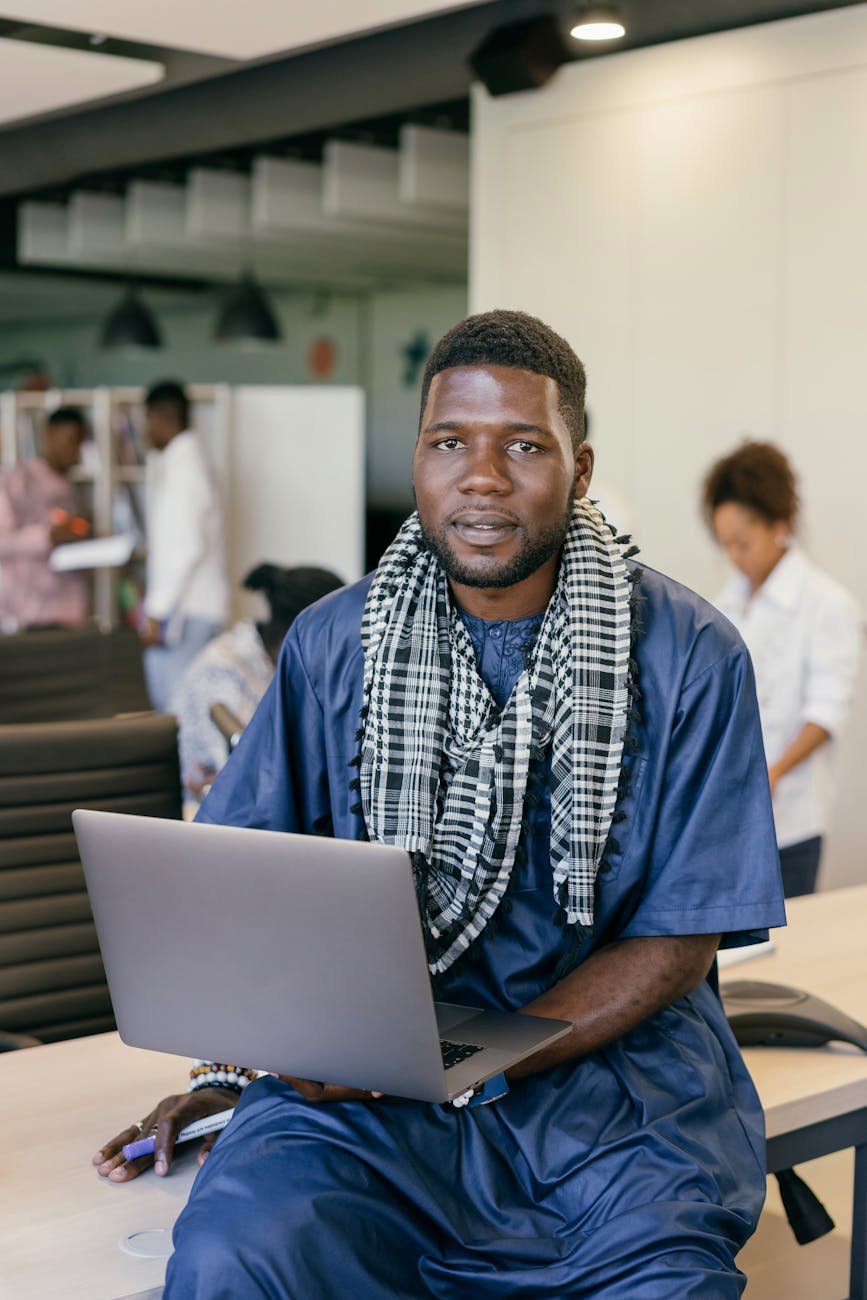 man with a scarf sitting with a laptop
