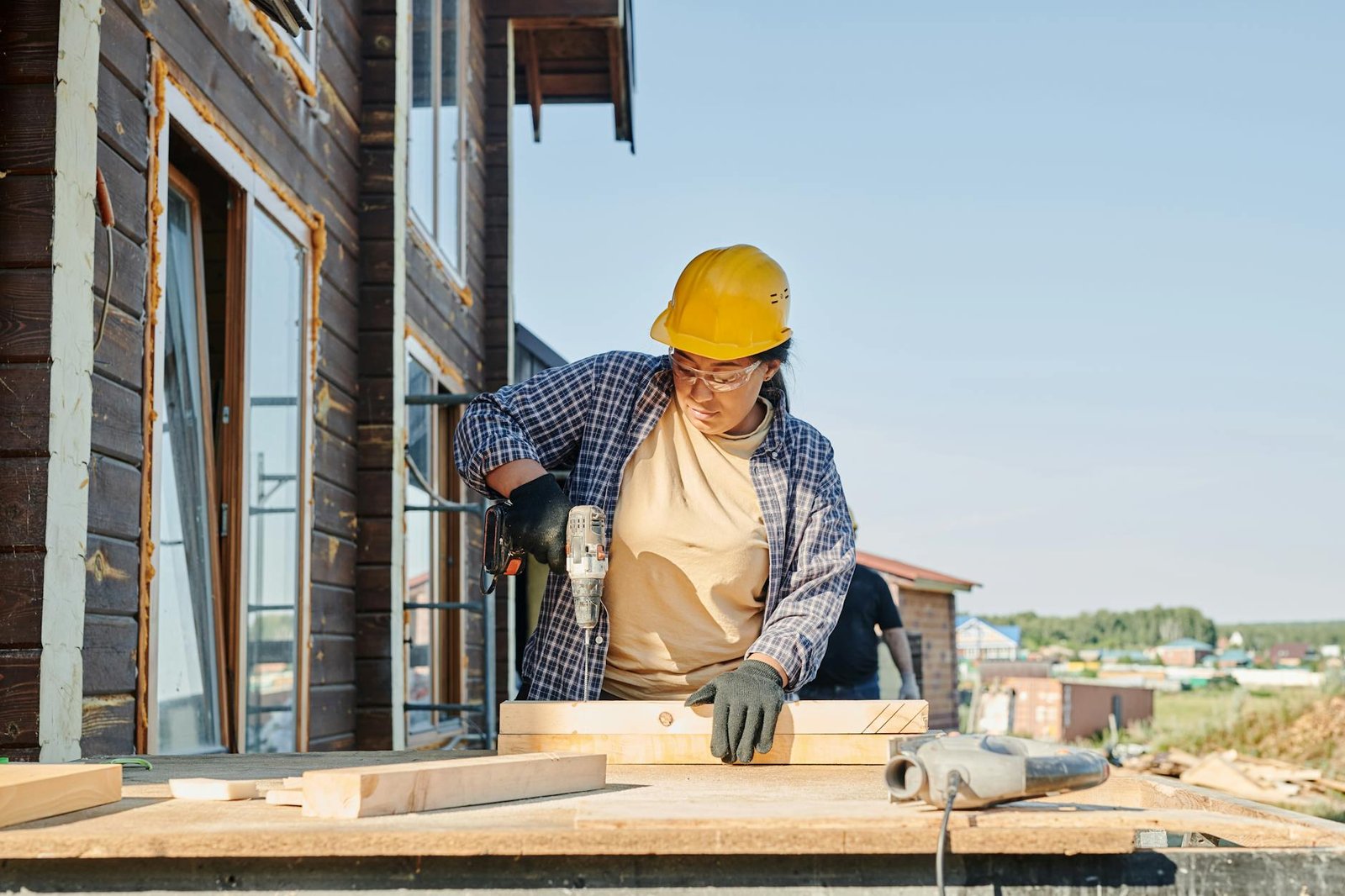 a woman in plaid long sleeve shirt holding a power tool