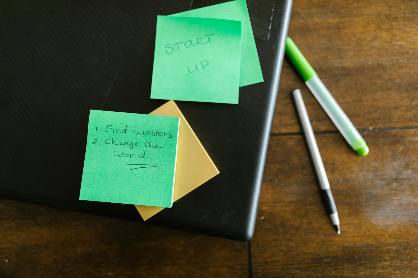 green sticky note beside white and green pen