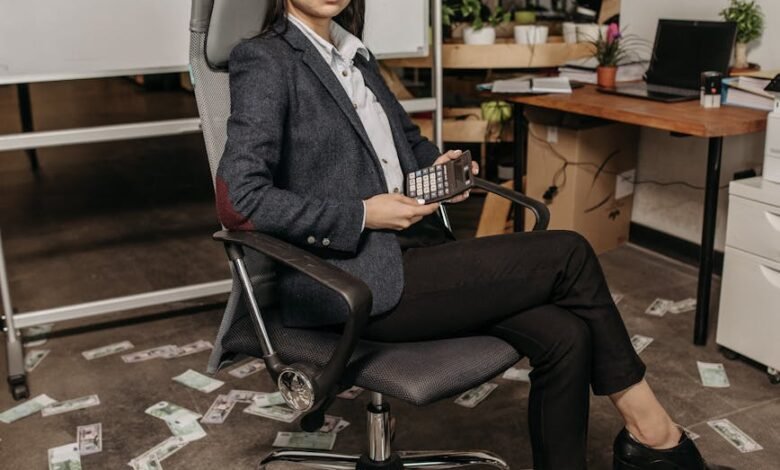 woman sitting on a gray swivel chair holding a calculator