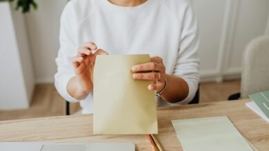 person wearing a sweater holding a brown envelope