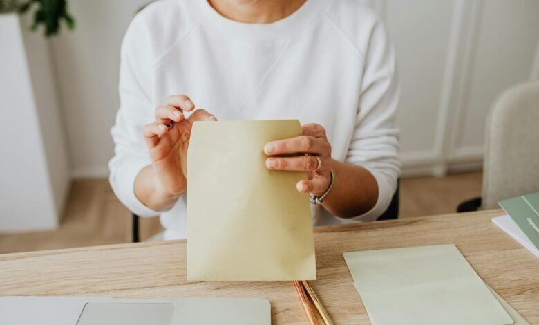 person wearing a sweater holding a brown envelope