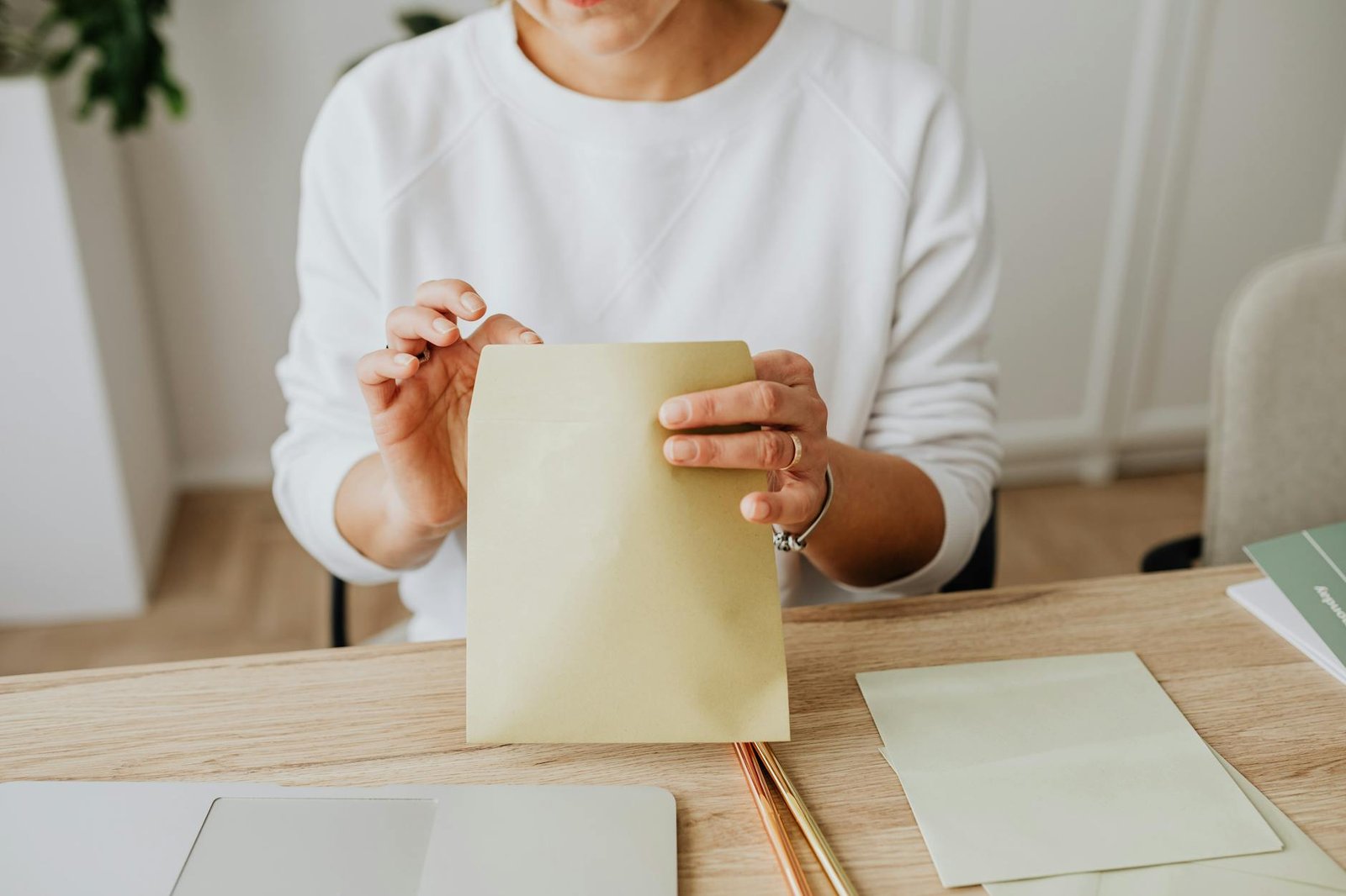 person wearing a sweater holding a brown envelope