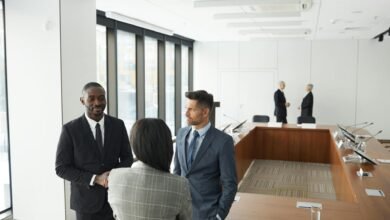 men in suit jackets standing in front a person in gray plaid jacket