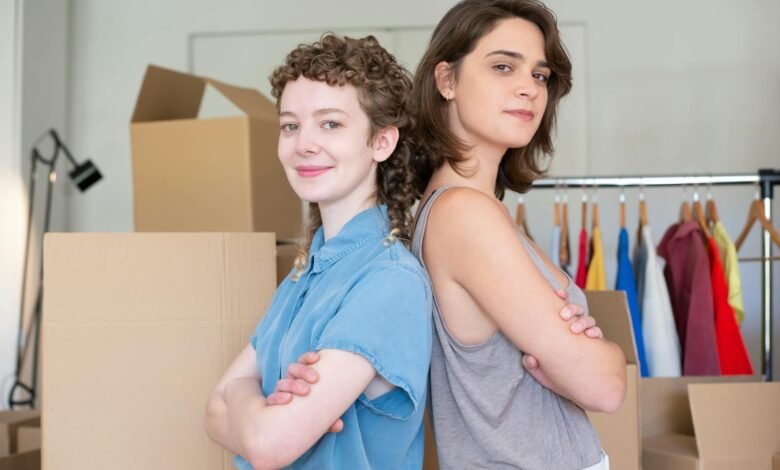 a woman in blue button up shirt standing beside a woman in gray tank top