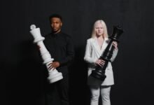 man and woman standing while holding chess pieces