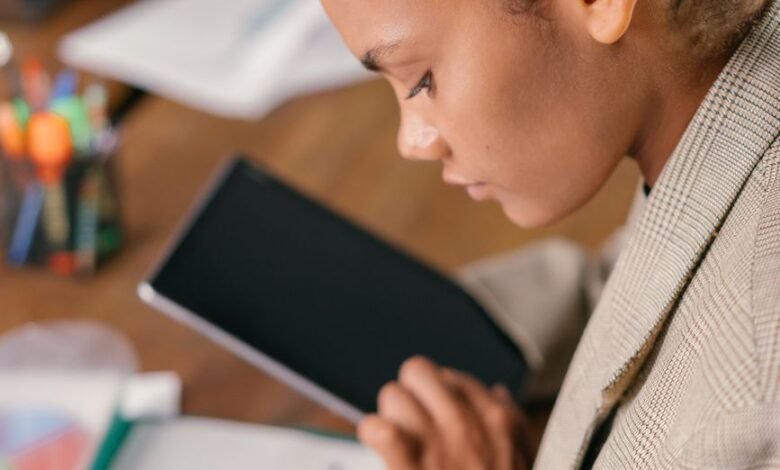 woman holding a tablet looking at a chart on paper