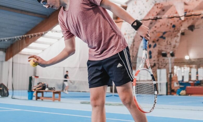 man in red t shirt and black shorts playing tennis